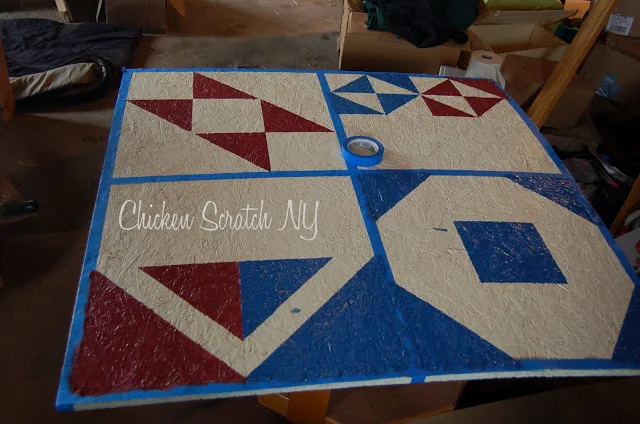 plywood sheet taped in a pattern and being painted to make a barn quilt