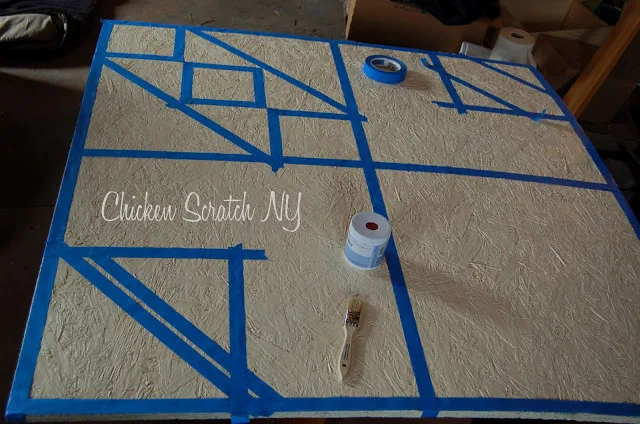 plywood sheet painted cream and maked with blue tape to make a barn quilt