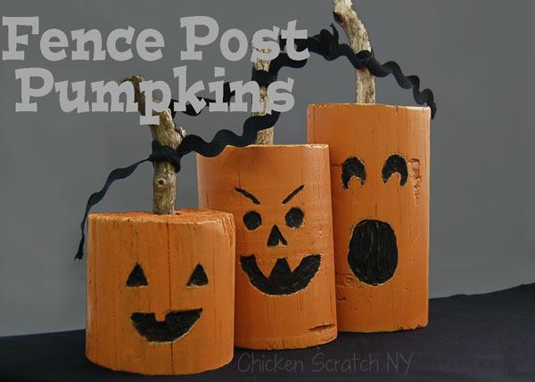 wooden fance posts with carved faces turned into Halloween jack-o-lanterns