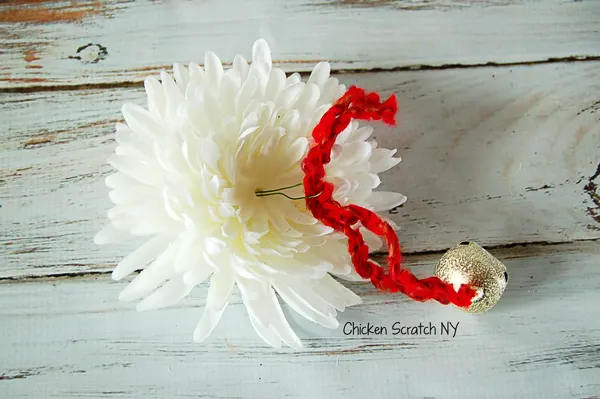 Decorate a festive holiday yarn wreath with reassembled jingle bell flowers