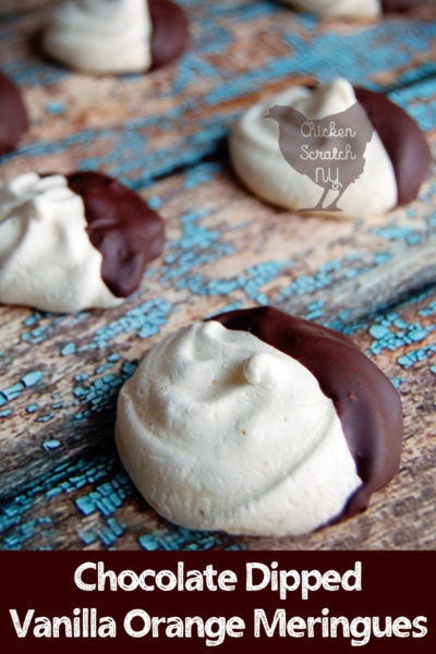 white vanilla meringue cookies dipped in dark chocolate on a blue and brown wooden backdrop