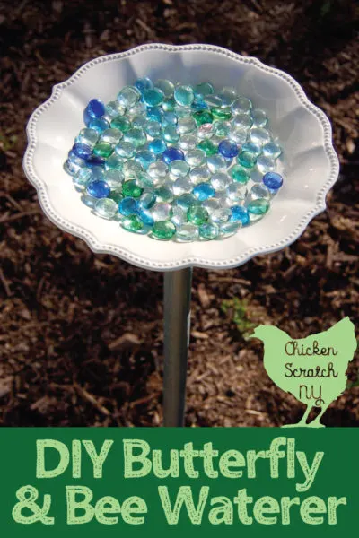 glass dish filled with blue and green glass gems on a metal pole for a DIY bee waterer
