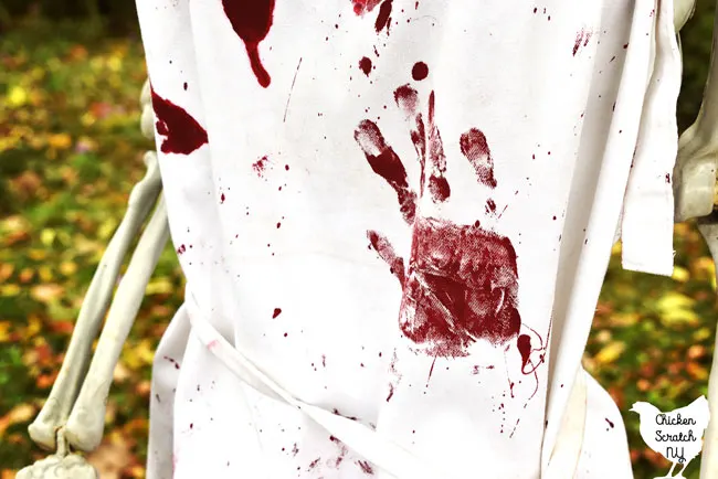 close up shot of white apron covered with bloody Halloween hand prints and blood splatters 