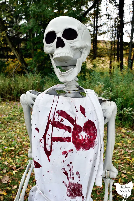 life sized halloween skeleton wearing a white Bloody Halloween Apron