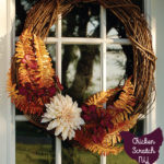grapevine wreath on white front door with gold ferns, purple dogwood and a large white dahlia