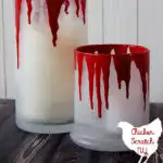 Frosted glass candle holders with fake blood dripping down and text overlay for DIY candle tutorial