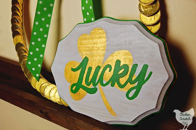 chocolate coin st. patrick's ay wreath on wooden shelf with white, gold and green sign that says lucky