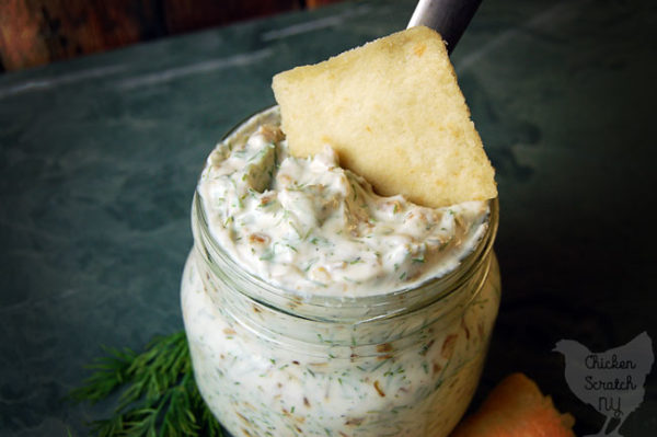 caramelized onion sip in a glass jar with pita chips on green tile