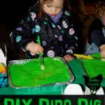 little girl using paintbrush to dig through green play sand for dinosaur bones