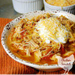 white bowl filled with instant pot chicken dinner with tomatoes and pineapple on an orange towel with two small white bowls filled with shredded cheese and greek yogurt