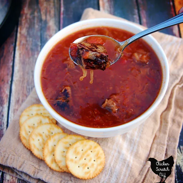 white bowl filled with tomato, sauerkraut and beef soup with ritz crackers and crock pot