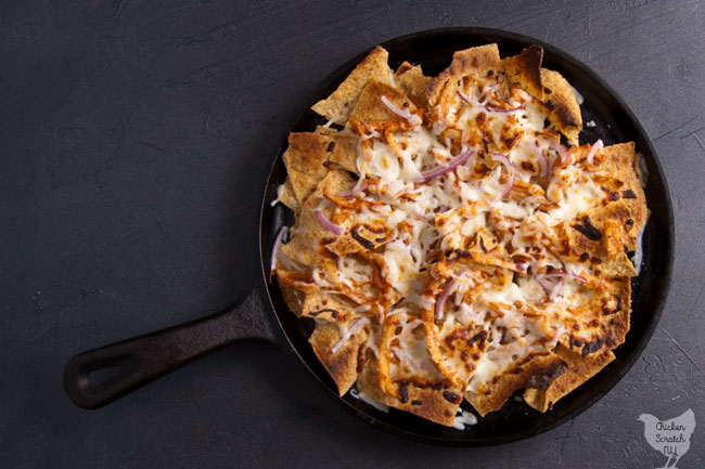 BBQ chicken nachos with red onion and mozzarella cheese on a cast iron griddle