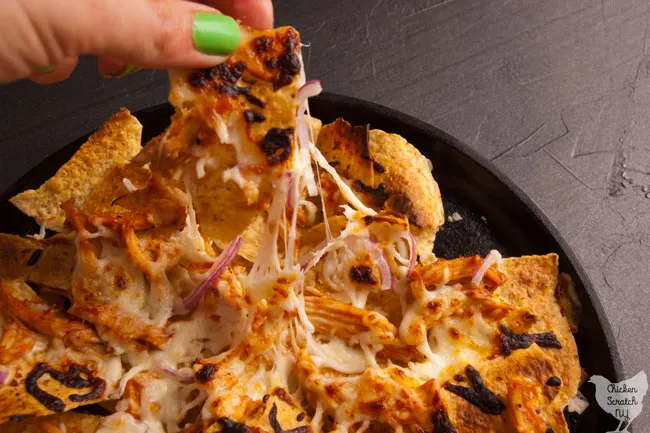 BBQ chicken nachos with red onion and mozzarella cheese on a cast iron griddle