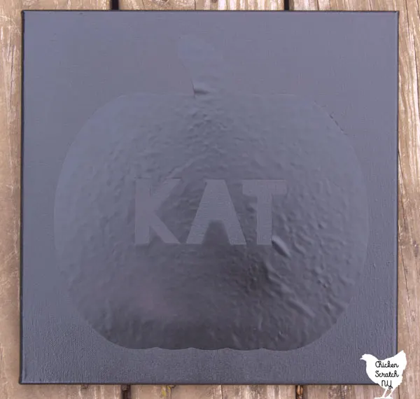 single canvas spray painted black with Pumpkin stencil with the name KAT in the center