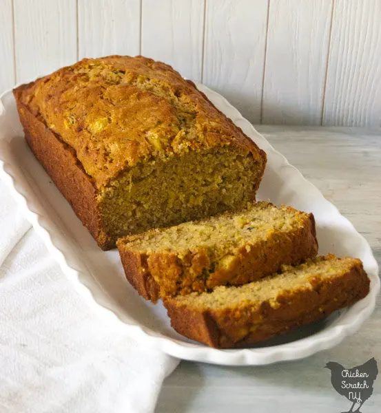 sliced loaf of pineapple zucchini bread on a scalloped edge white dish