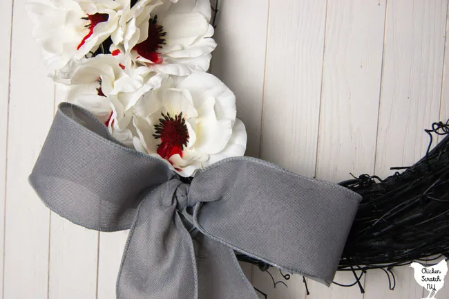 grey boy from wired ribbon on a black wreath with bloody white flowers