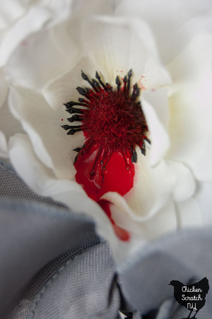 white flower with red paint 'blood' dripping from the center