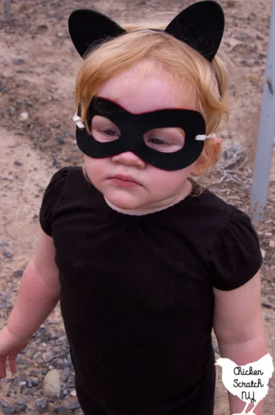 little blonde girl in black shirt with black superhero mask and black cat ears