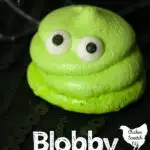 lime green meringue cookie with eyes that look like Blobby from Hotel Transylvania on a black surface
