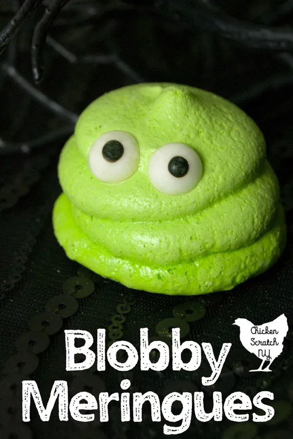 lime green meringue cookie with eyes that look like Blobby from Hotel Transylvania on a black surface