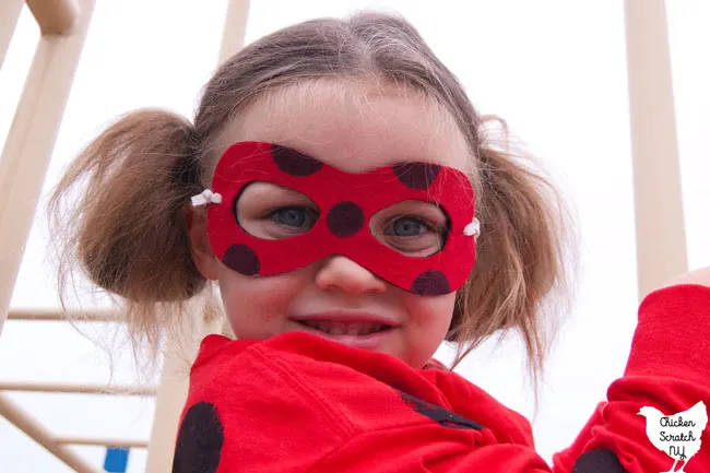 little girl wearing a homemade miraculous ladybug costume and mask