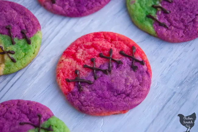 multi colored sugar cookies 'stitched' together with fake chocolate stitched to look like Sally's dress from The Nightmare Before Christmas on a whitish blue wooden background