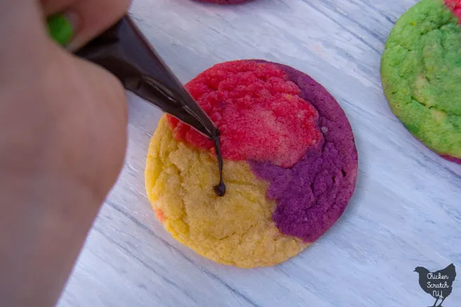 multi colored sugar cookies 'stitched' together with fake chocolate stitched to look like Sally's dress from The Nightmare Before Christmas on a whitish blue wooden background