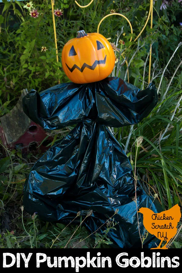 garden stake turned onto a Halloween garden sculpture with a small fake pumpkin, trash bag and zip ties standing in a late summer garden