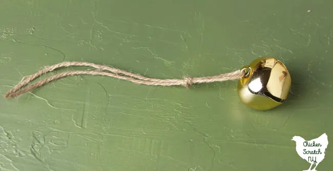 gold bell threaded onto twine and tied in a knot