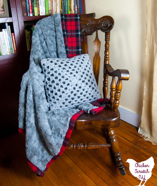 grey fur and red plaid flannel blanket sitting on a rocking chair with a crocheted pillow cover