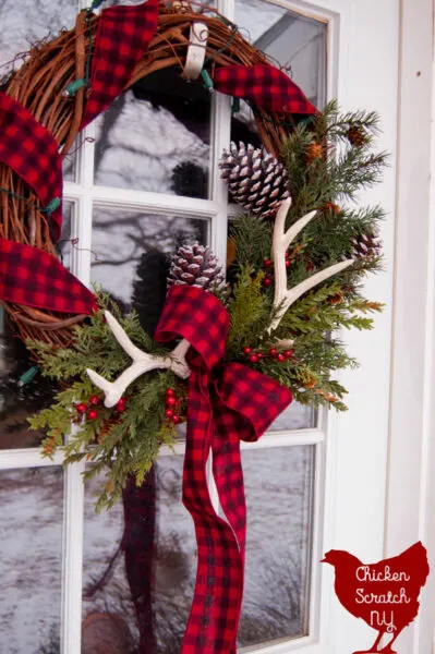 rustic country Christmas wreat with antlers, pine cones and buffalo check ribbon