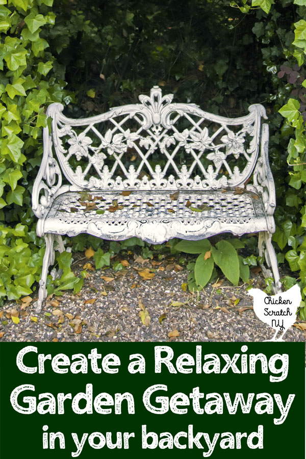 white metal bench on a stone path surrounded by ivy