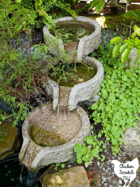 garden waterfall fountain with three levels surrounded by green plants