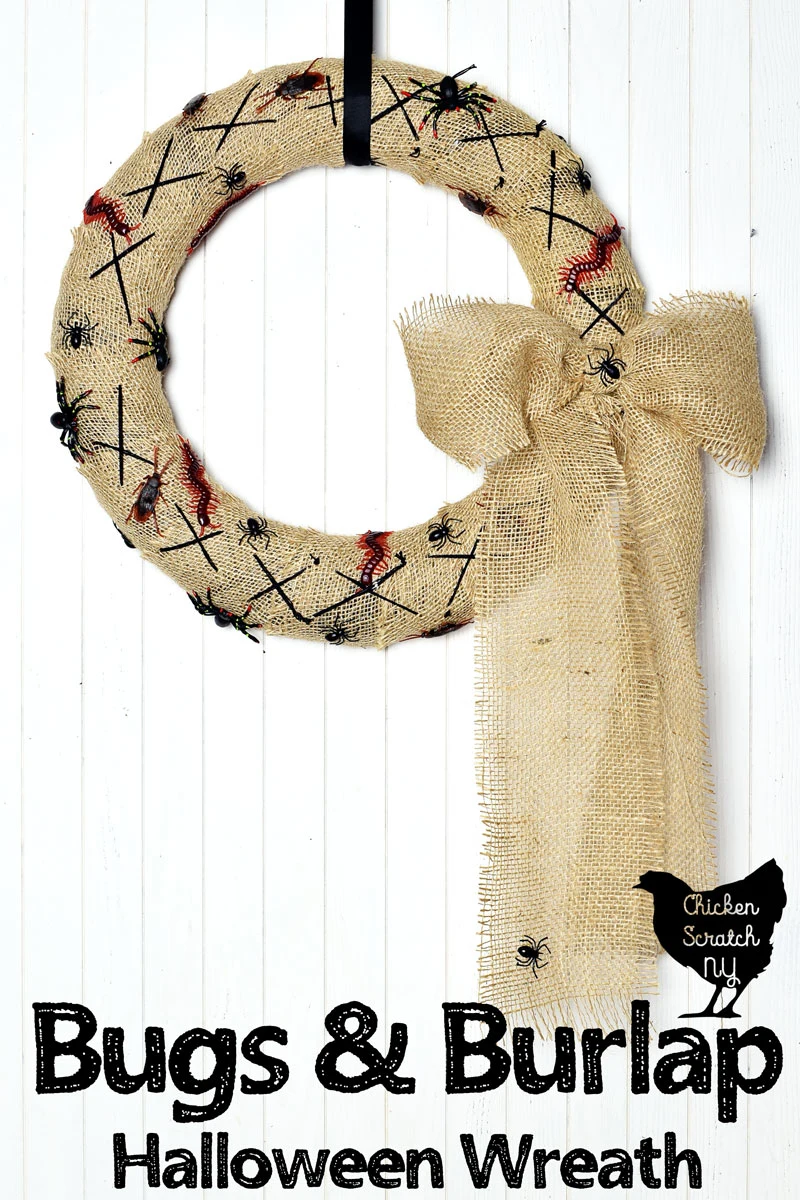 burlap covered Halloween wreath with fake bugs and spiders with a burlap bow hanging on a white wall with a black ribbon