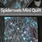 small square spiderweb mini quilt with hand embroidery on galaxy print fabric with a crystal button spider