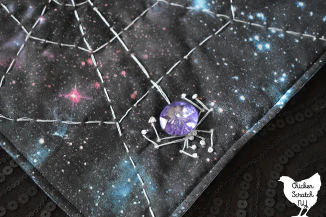 purple crystal button spider on a galaxy print spiderweb mini quilt