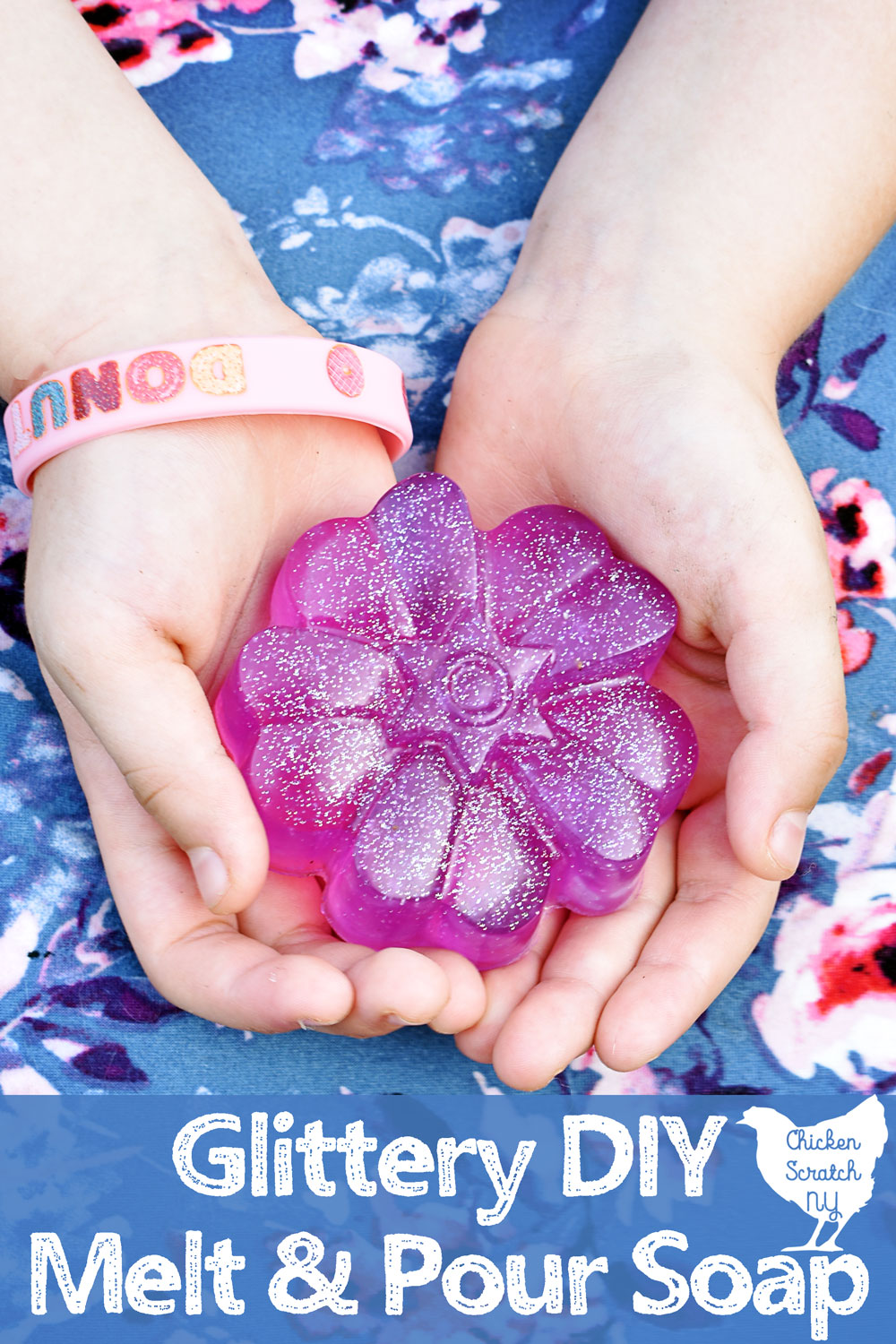 little girls hands holding a purple flower shaped bar of soap with holographic glitter