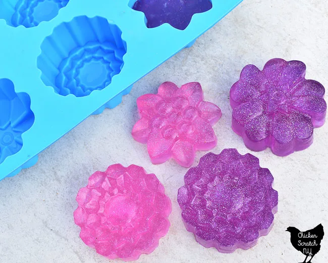 pink and purple melt and pour soap bars made with a floral silicone mold and holographic glitter
