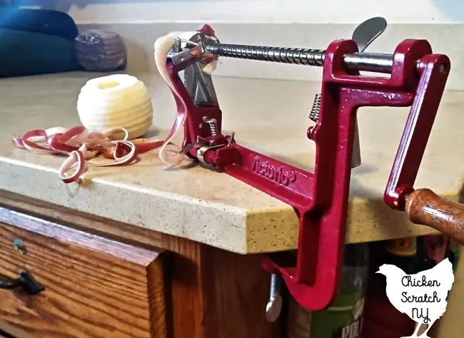 apple peeler corer slicer clamped to counter with peeled apple