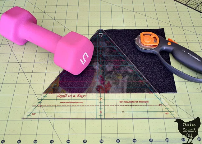 60 degree ruler on black fabric with rotary cutter and weight