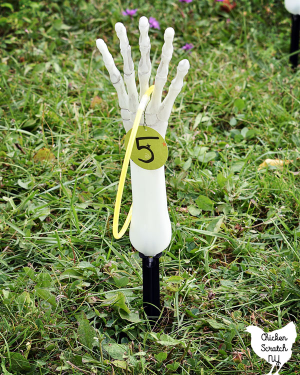 skelton hand with glowstick necklace ring on is as part of a skeleton ring toss Halloween Party game 