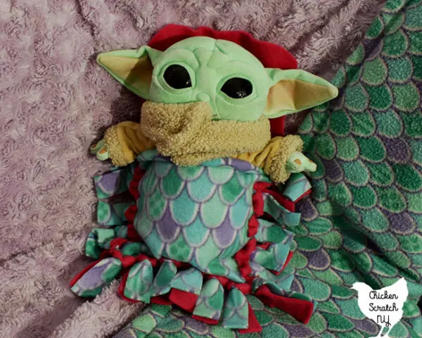 baby yoda stuffed animal in a fleece sleeping bag