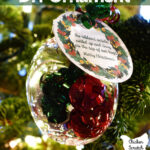 plastic ornament filled with curling ribbon with a gift tag with a poem about hugs hanging in a Christmas tree with white lights and red ornaments