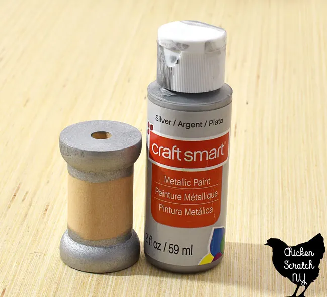 paint the top and bottom sections of a wooden spool with metallic silver paint