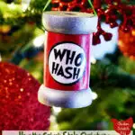 wooden spool ornament hanging in a Christmas tree with a homemade label saying "Who Hash"