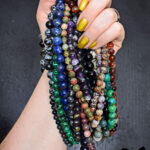 hand holding a pile of homemade DIY beaded gemstone necklaces