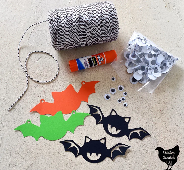 supplies for Halloween bat garland made with card stock paper, googly eyes, a glue stick and bakers twine