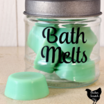 glass jar with black lid and black vinyl text "Bath Melts" in a script font filled with green bath melts with text overlay "bath melts recipe with jar tutorial"