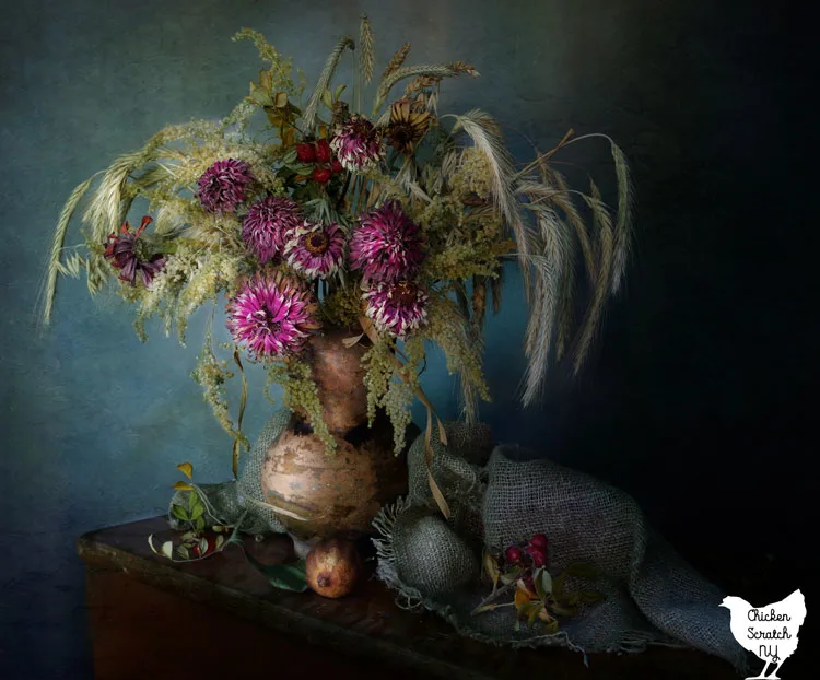 vase with dried flowers against a blue background