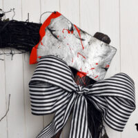 sleepy hollow inspired wreath with black and white striped bow and fake axe with blood splatter on it
